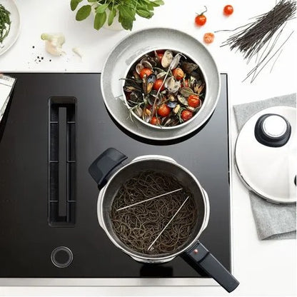 Stovetop with pots of food and ingredients on a white surface