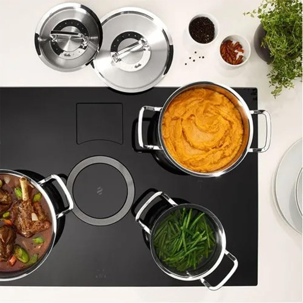 Stovetop with pots containing different dishes on a white surface.