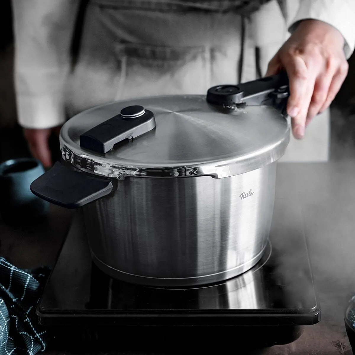 Person holding a pressure cooker on a stove